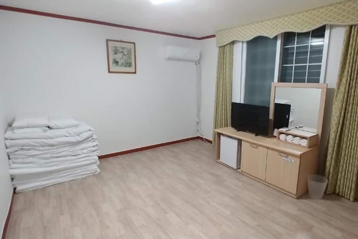 Een hotelkamer met een bed, een bureau met spiegel, een televisie en een raam met gordijnen.