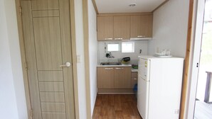 Cocina compacta con armarios de madera, un lavamanos y un refrigerador.