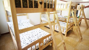 Camas literas con colchón estampado, armazones de madera y suelo de baldosas.