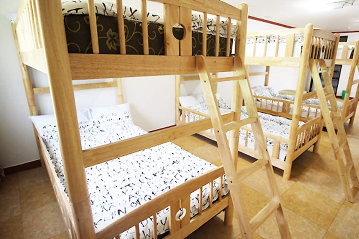 Tweepersoonsbed met een gestreept matras, houten frames en een betegelde vloer.