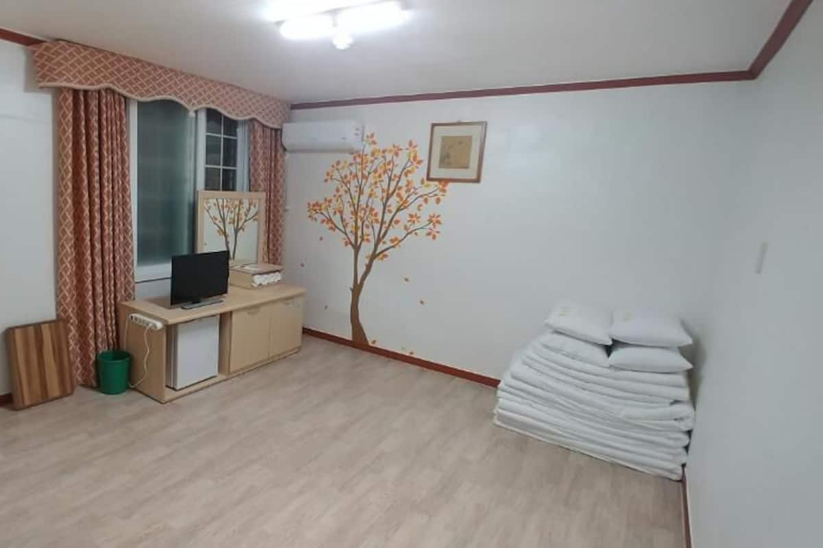 Een kamer met een bureau, stoel en een wandairconditioning.