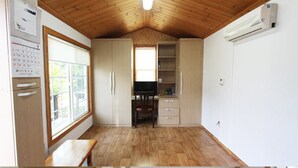 Una cocina pequeña y funcional con suelo de madera, una ventana y un televisor empotrado.