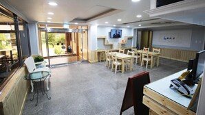 Amplio espacio interior con una mesa de comedor y sillas, una mesa de vidrio y un mostrador de recepción con computadora y teléfono.