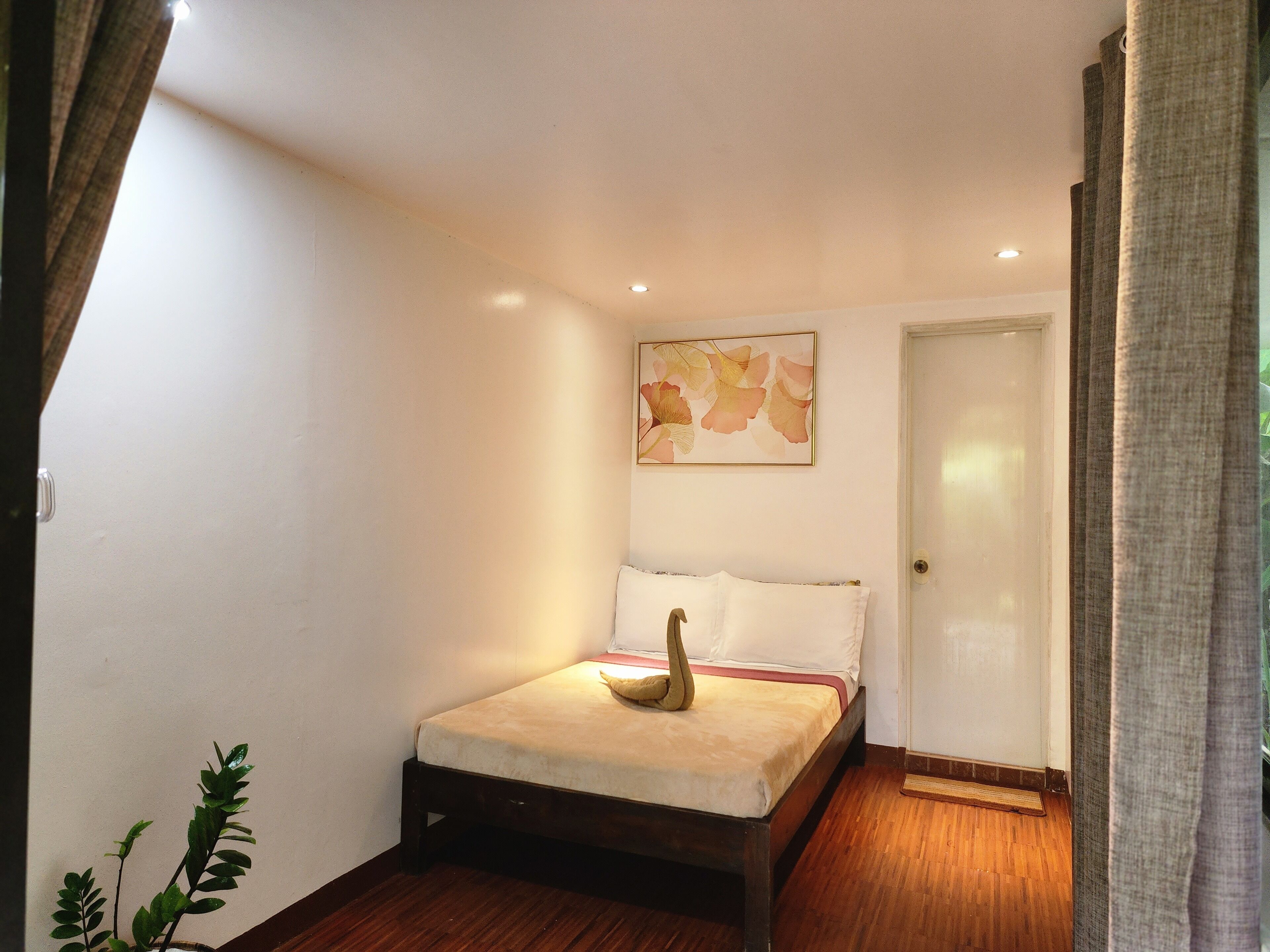 Une chambre à coucher avec un lit, une porte, une œuvre d’art accrochée au mur et une plante en pot.