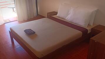 Una cama bien hecha con un cojín y una mesita de noche de madera, un armario ropero de madera.