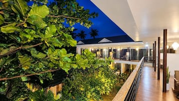 A modern building with a wooden deck and lush greenery.