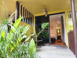A hotel entrance with a yellow wall, a wooden column, and a hanging light fixture. - Soeliana Resort (General Luna)