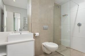 A modern bathroom with a white sink, toilet, and glass shower enclosure. - The Sentinel 1310 (Cape Town)
