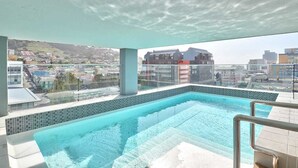 A rooftop infinity pool with a clear view of the cityscape and hills in the background. - The Sentinel 1310 (Cape Town)
