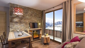 A cozy living room with a fireplace, a dining area, and a sofa with a view of snow-capped mountains. - Modern Comfort by the Slopes (Tignes 1800)