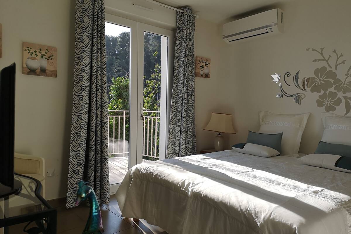 A bedroom with a bed, a TV, a lamp, and a balcony with patterned curtains.