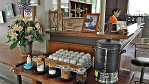 Un coin bar équipé d’une machine à café, d’un grand vase rempli de fleurs et d’un plateau de tasses.