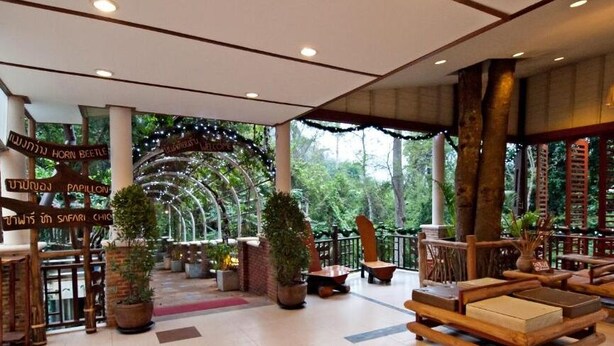 Un hall d’entrée spacieux, agrémenté de meubles en bois, de plantes en pot et de panneaux indicateurs.