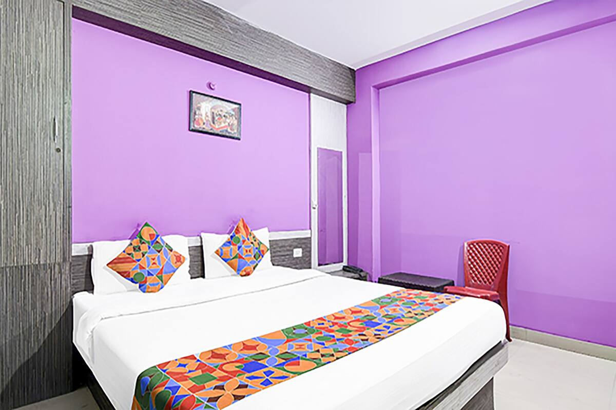 Ein Hotelzimmer mit einem Bett, einem roten Sessel und einer violetten Wand.