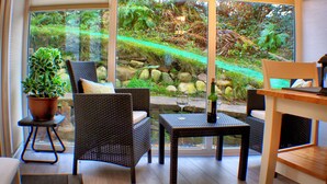 A conservatory with wicker furniture, a potted plant, and a view of a garden through large glass doors. - Romantic, quirky, unique cottage, big garden, free parking, pet friendly max 2 (Beckermet)