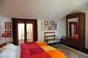 Ein Hotelzimmer mit Bett, einer Sitzbank, einem Kleiderschrank und einer Wand mit gerahmten Bildern.