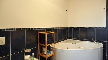 Un bagno con una vasca, uno scaffale di legno con asciugamani, un water e un lavandino.