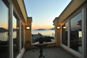 Ein Balkon mit großen Fenstern, einem Blumentopf und einem Schlauch auf dem Boden.