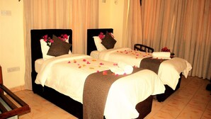A hotel room with two beds, each with a headboard, white linens, and decorative pillows. - Regency Inn (Mombasa)