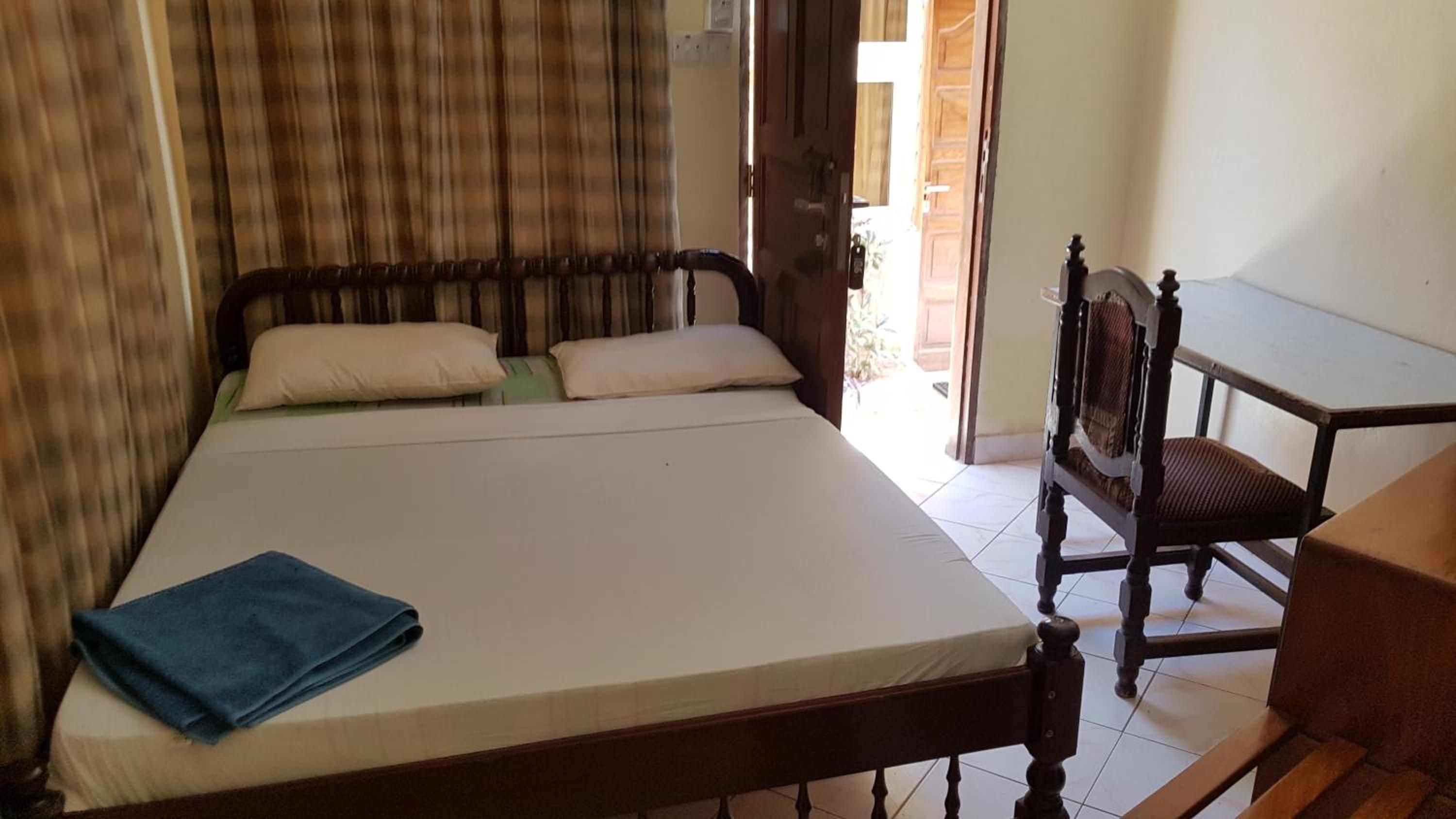A room with a bed, a chair, and a wooden table.