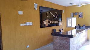 A reception area with a sign reading "The Regency Inn," a marble counter, and a window with blinds. - Regency Inn (Mombasa)