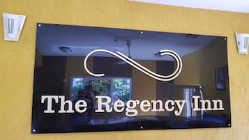 A sign for The Regency Inn with a reflective surface.