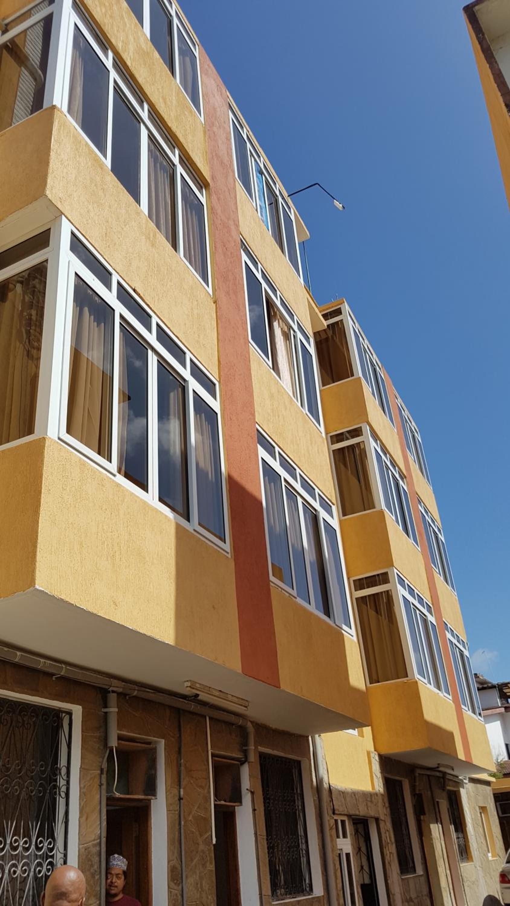 Un immeuble à plusieurs étages, doté d’une façade jaune, de nombreuses fenêtres et de balcons.