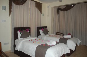 Habitación de hotel con dos camas, cada una con un cojín y un arreglo floral.