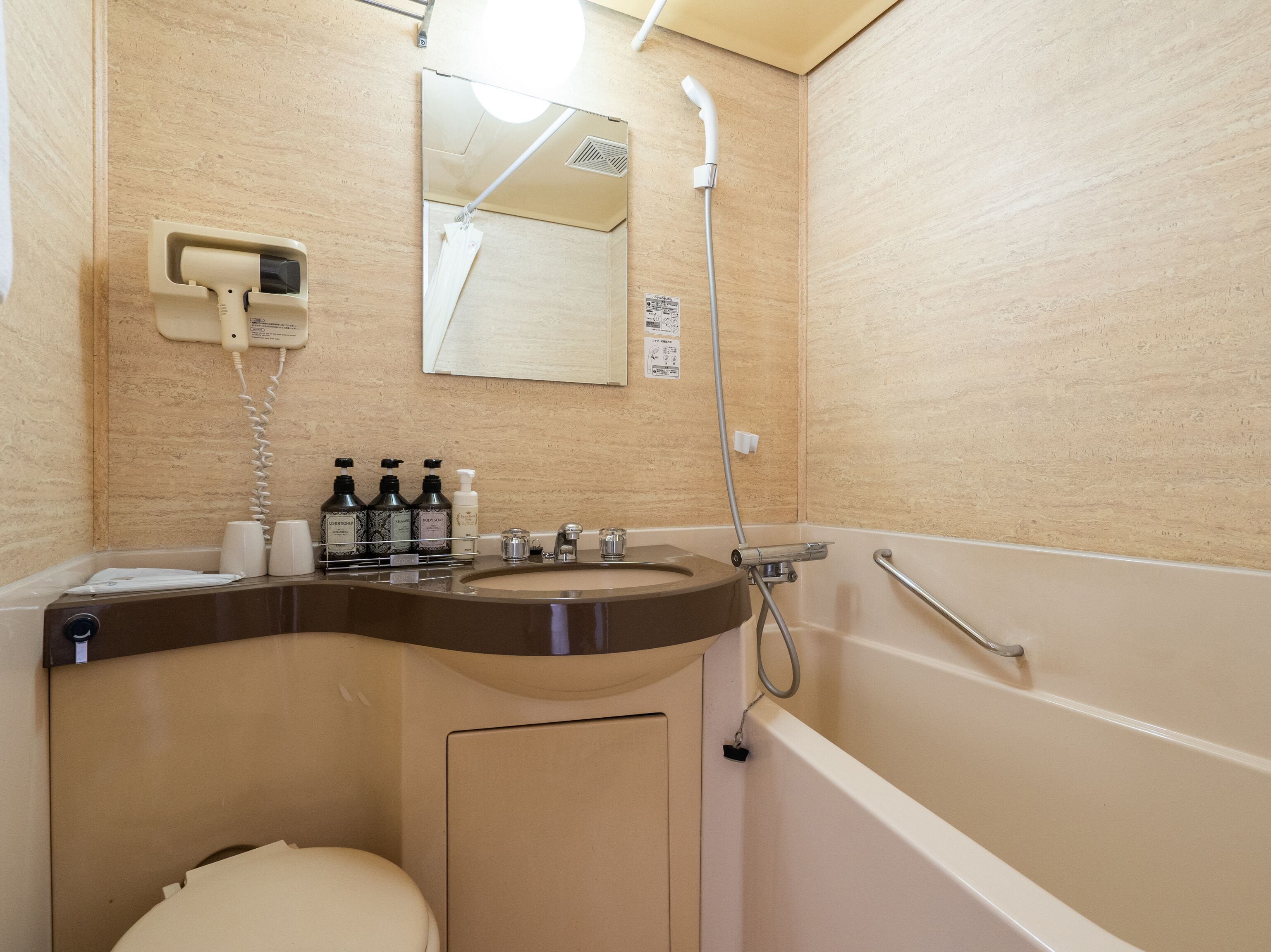 A bathroom with a sink, toilet, and shower. There are toiletries on the sink and a mirror above it.