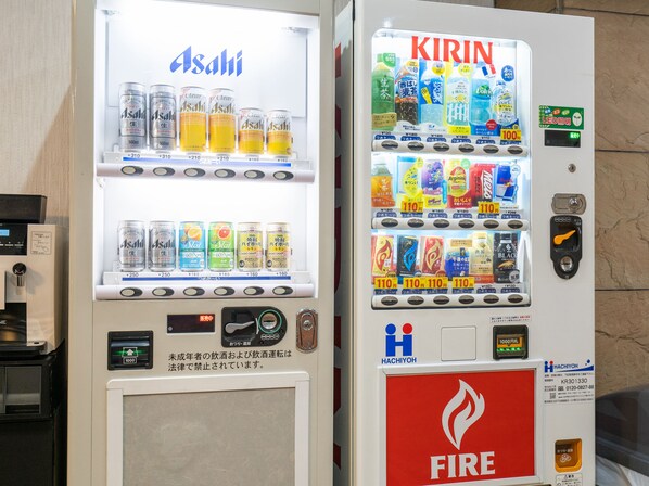 Máquinas de venda automática com bebidas Asahi e Kirin, um extintor de incêndio e o logotipo Hachiyoh.