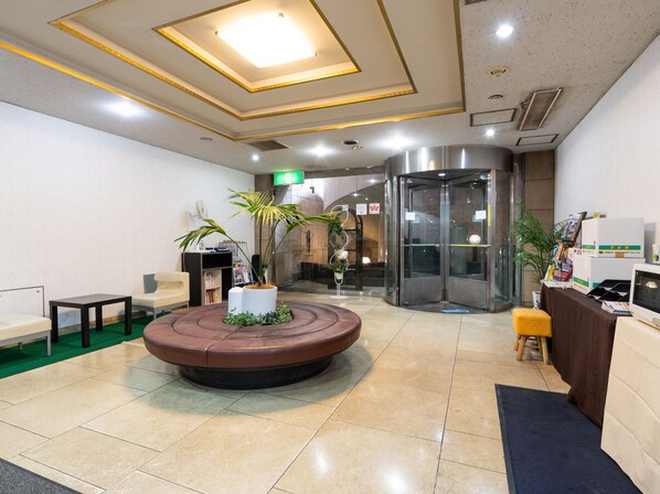 A lobby with a round seating area, a reception desk, and a revolving door.