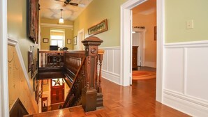 A wooden staircase with a handrail, leading to a room with a dining table and chairs. - Meritage House - Excellent Location, King St. NOTL (Niagara-on-the-Lake)