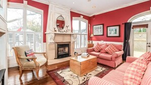 A living room with a fireplace, a sofa set, a wooden coffee table, and a chair with a Union Jack cushion. - Meritage House - Excellent Location, King St. NOTL (Niagara-on-the-Lake)