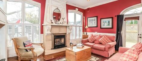 A living room with a fireplace, a sofa set, a wooden coffee table, and a chair with a Union Jack cushion.