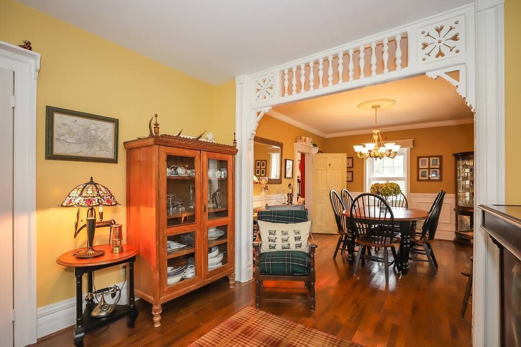 A dining area with a wooden cabinet, a plaid chair, and a chandelier.
