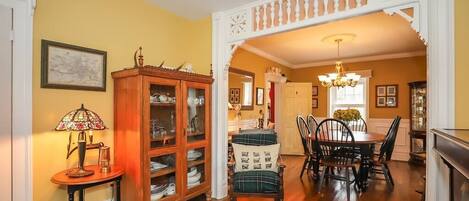A dining area with a wooden cabinet, a plaid chair, and a chandelier.