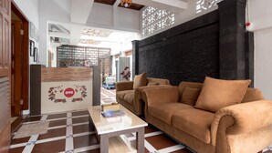 A modern living room with a sofa, coffee table, and decorative wall. - OYO 619 Naufal Guest House Syariah (Medan)