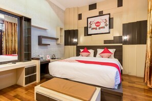Una habitación de hotel con cama, mesita de noche y escritorio con espejo.