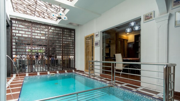 An indoor swimming pool with a tiled floor, metal railings, and a wooden partition with a grid pattern. - OYO 619 Naufal Guest House Syariah (Medan)