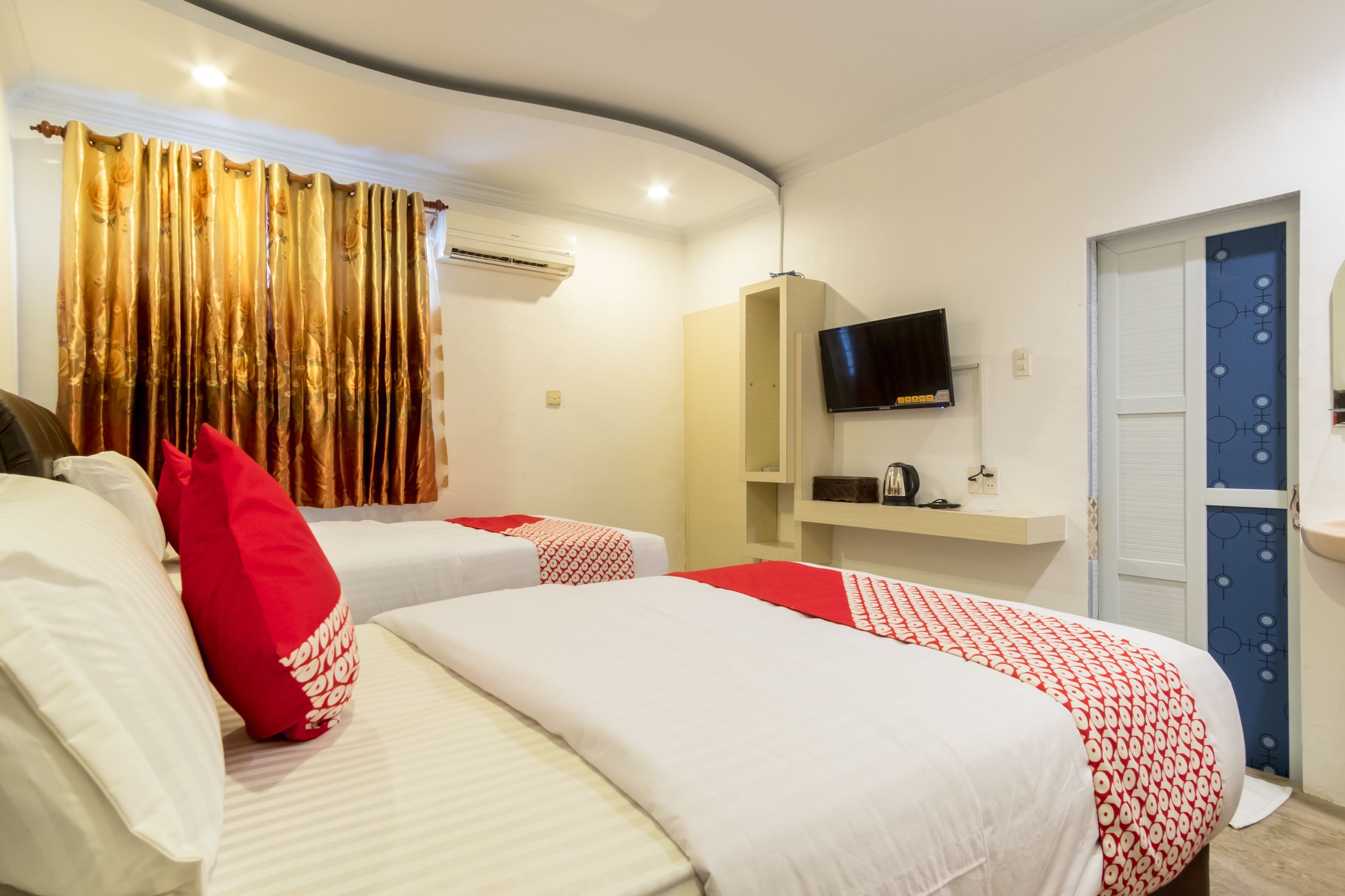 Une chambre d’hôtel avec deux lits, une télévision, une armoire et une porte de salle de bain.
