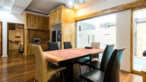 A modern kitchen with wooden cabinets, a dining table with chairs, and a large window providing natural light. - OYO 619 Naufal Guest House Syariah (Medan)