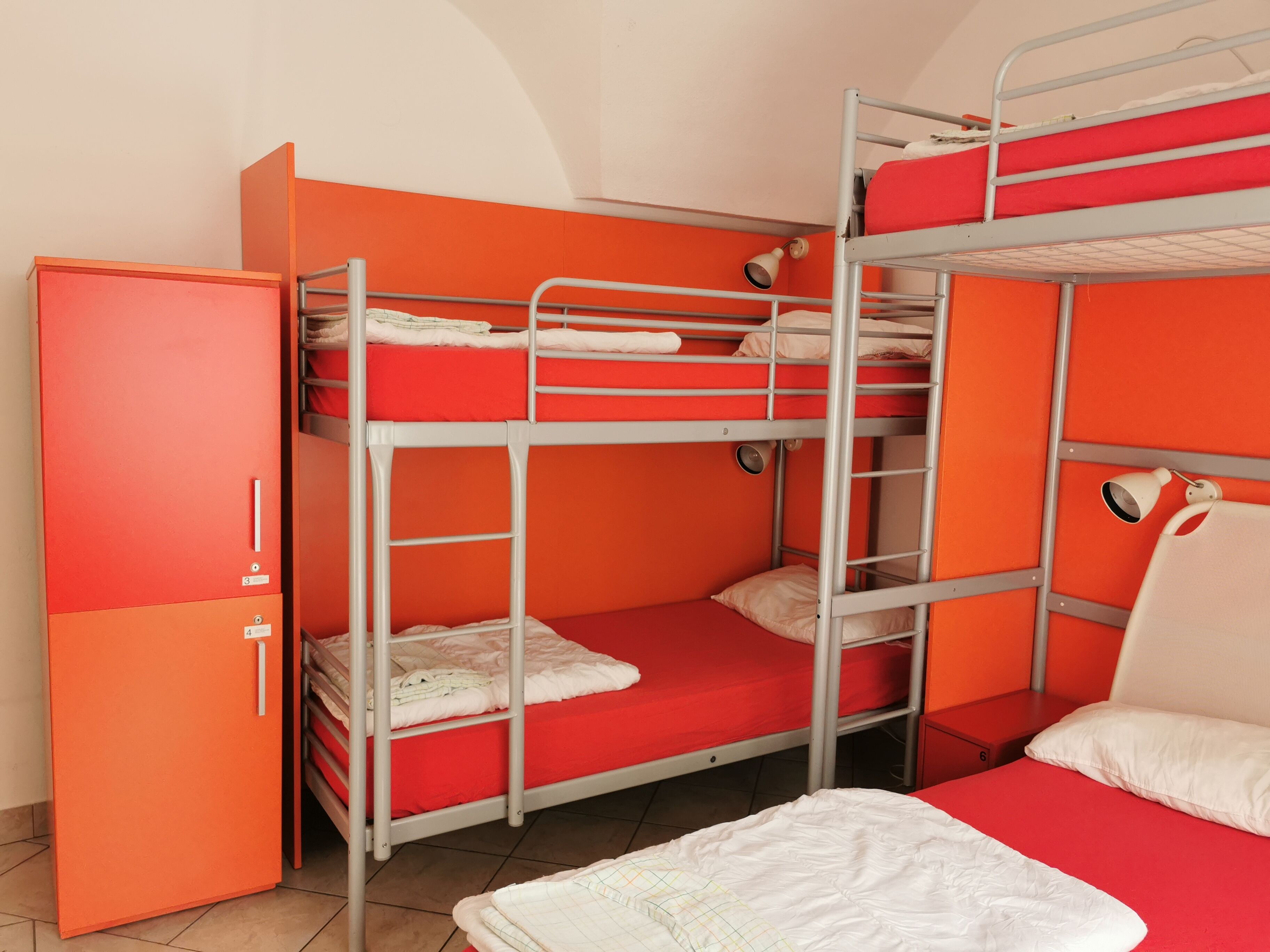 Een slaapkamer met stapelbedden, oranje wanden en metalen leuningen.