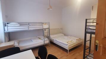 Un dormitorio con literas, una mesa, sillas y una puerta.