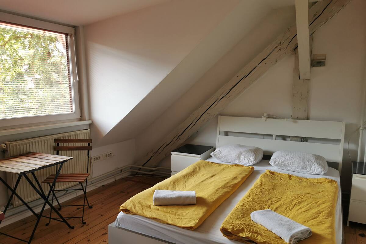 A room with a bed, a small table, and a window.