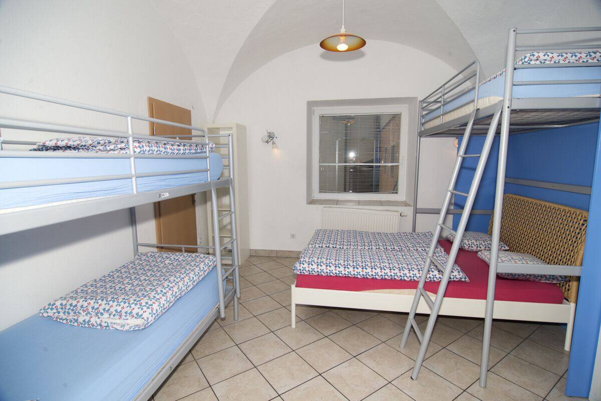 A bunk bed room with a window, a radiator, and a ladder.