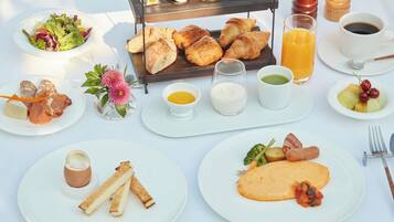 A breakfast buffet with various dishes, including croissants, eggs, and fruits.