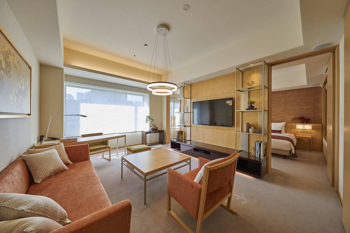 Una habitación de hotel moderna con sofá, mesa de comedor, televisor y cama.