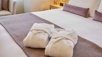 A neatly made bed with a brown blanket and two white towels folded on top.