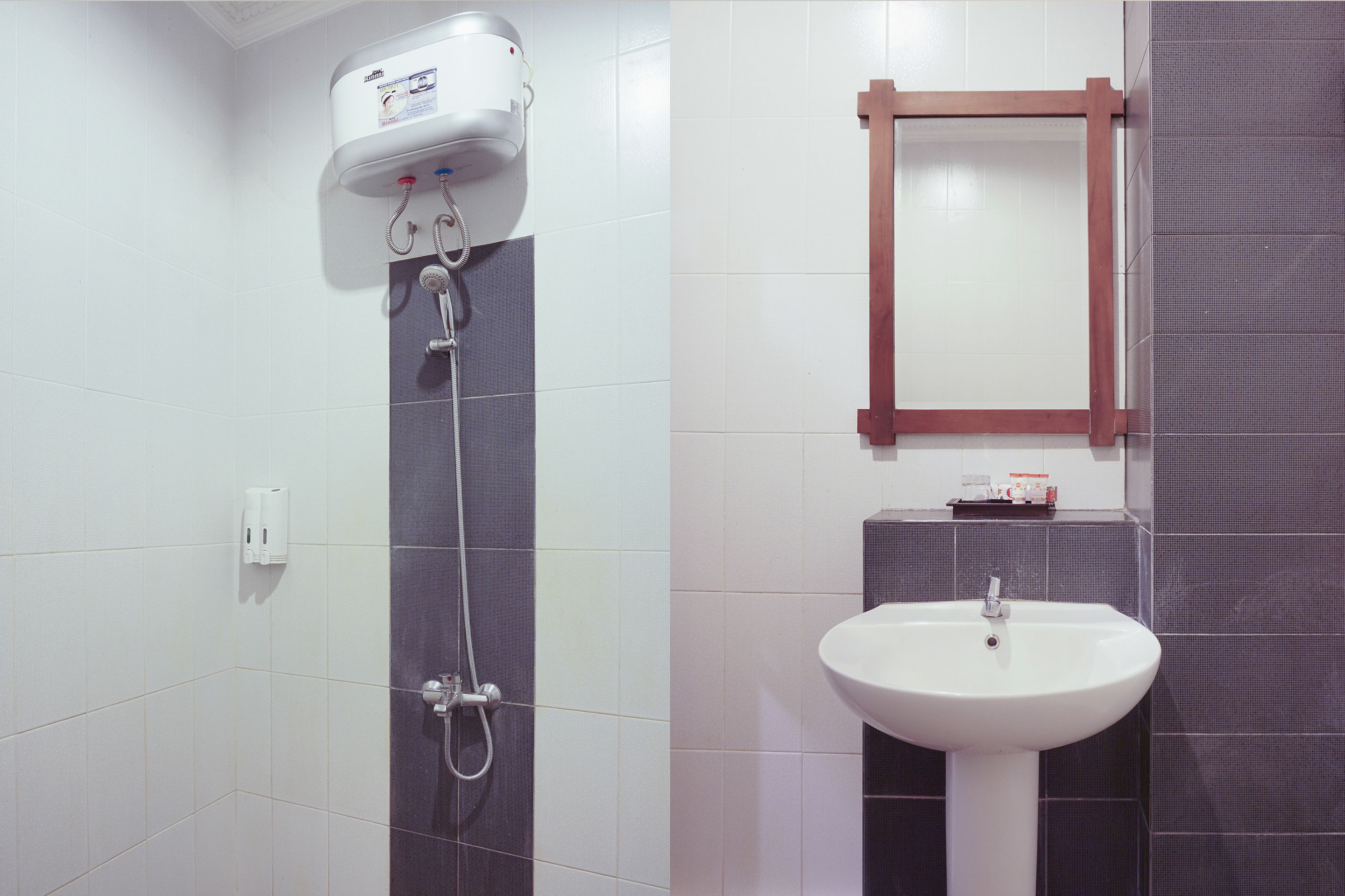 A bathroom with a white toilet, a shower with a white hose, and a white sink with a mirror above it.