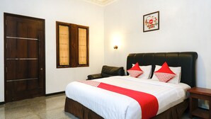 A neatly made bed with a red and white bedspread, a wooden headboard, and a small bedside table. - Super OYO OYO Capital O 514 Omah Pari Boutique Hotel (Yogyakarta)
